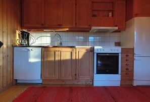 Eine Küche mit Holzschränken, einem weißen Geschirrspüler, einem Herd und einem Kühlschrank.