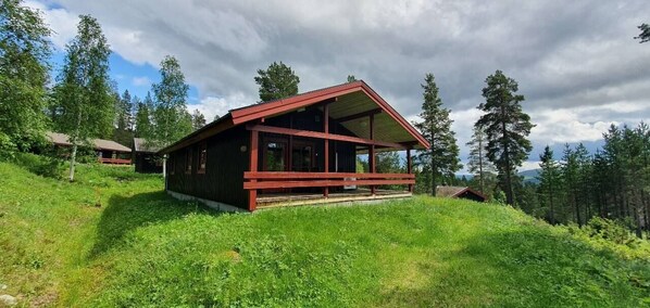 A wooden cabin with a sloped roof, surrounded by lush greenery and trees. - Sauna | Wi-Fi | Terrace | Wood stove | Cable TV (Lofsdalen)