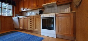 A kitchen with wooden cabinets, a white stove, and a blue rug. - Sauna | Wi-Fi | Terrace | Wood stove | Cable TV (Lofsdalen)