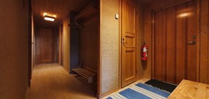 A hallway with wooden doors, a fire extinguisher, and a blue rug. - Sauna | Wi-Fi | Terrace | Wood stove | Cable TV (Lofsdalen)