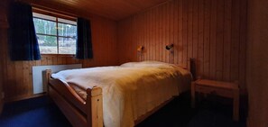 A wooden cabin room with a bed, a chair, and a window with curtains. - Sauna | Wi-Fi | Terrace | Wood stove | Cable TV (Lofsdalen)