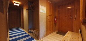 Ein Flur mit einer Holztür, einem blau-weiß gestreiften Teppich und einer hölzernen Bank.
