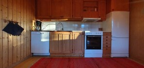 A compact kitchen with wooden cabinets, a coffee maker, a dishwasher, a stove, and a refrigerator.