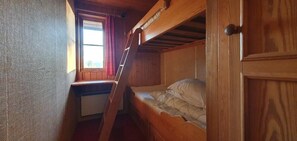A bunk bed room with a window, wooden walls, and a door.