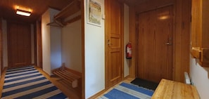 Ein Korridor mit Holztüren, einem Feuerlöscher und einem blau gestreiften Teppich.