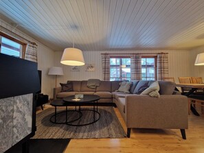 Ein Wohnzimmer mit einer Couch, Sesseln, einem Couchtisch und einem Esstisch.
