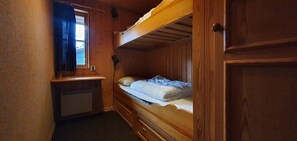 Ein Zimmer mit einem Holzbett, Schreibtisch und Fenster.