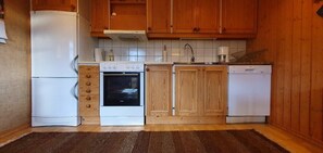 Eine Küche mit Holzausstattung, einem weißen Kühlschrank, einem Backofen und einem Geschirrspüler.