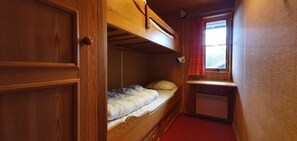 Ein Schlafraum mit Etagenbetten, einem Fenster, Holzwänden und einem roten Teppich.