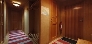 Ein Flur mit Holztüren, einem rot-weiß gestreiften Teppich und einem an der Wand befestigten Feuerlöscher.