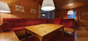 Ein Holzkaminzimmer mit einem roten Sofa, einem Holztisch und zwei Pendelleuchten.