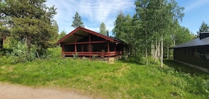 Eine Holzhütte mit rotem Dach, umgeben von Bäumen und Gras.