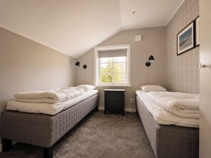 A small, single-bedroom room with two beds, a window, and a nightstand.