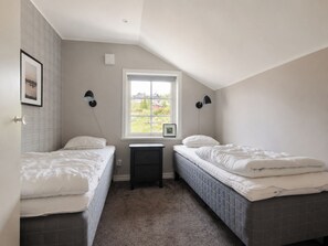 Un dormitorio con dos camas, una ventana y una mesita de noche pequeña.