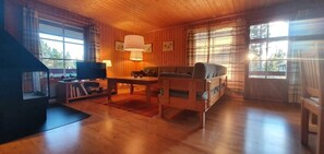 Ein Holzinnenraum mit Fernseher, Sofa, Tisch und Grillbereich.