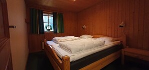 A wooden-paneled room with a single bed, a window with curtains, and a wall-mounted lamp. - Sauna | Wi-Fi | Terrace | Wood stove | Cable TV (Lofsdalen)