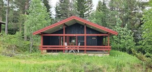A cabin with a red roof and wooden walls, surrounded by dense forest. - Sauna | Wi-Fi | Terrace | Wood stove | Cable TV (Lofsdalen)