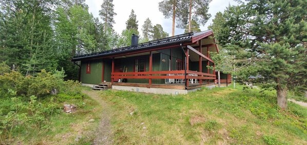 A cabin with a porch, surrounded by forest.