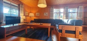 A wooden-paneled room with a sofa, a table, and a television.
