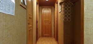 A narrow hallway with wooden doors, a textured wall, and a hanging decorative item. - Sauna | Wi-Fi | Terrace | Wood stove | Cable TV (Lofsdalen)