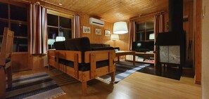 Ein Holzinnenraum mit einer Couch, einem Fernseher und einem Kamin.