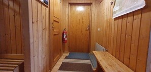 Ein mit Holz verkleideter Korridor mit einer Holzbank, einem Feuerlöscher und einer Tür.
