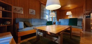 A wooden cabin interior with a sofa set, a wooden table, and a bookshelf. - Sauna | Wi-Fi | Terrace | Wood stove | Cable TV (Lofsdalen)