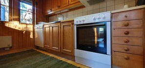 A kitchen with wooden cabinets, a white oven, and a green rug. - Sauna | Wi-Fi | Terrace | Wood stove | Cable TV (Lofsdalen)