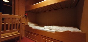 Ein Stockbett mit Holzkopfstütze, einem Nachttisch und einer Schublade.