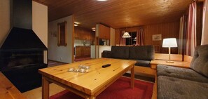 Ein Holzinnenraum mit Esstisch, Sofa und Kamin.