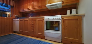 A kitchen with wooden cabinets, a white stove, and a blue rug.