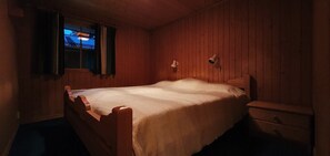 A single bed with a wooden headboard, a bedside table, and a nightstand.