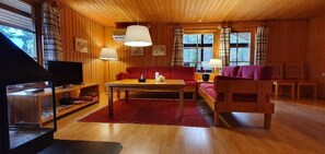 Ein Holzinterieur mit einer Couch, einem Tisch und einem Fernseher.