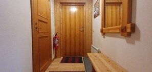 Eine Holztür mit einem Feuerlöscher, einer Bank und einem Heizkörper an der Wand.