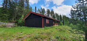 Eine rustikale Holzhütte mit rotem Dach, umgeben von einem Waldgebiet.