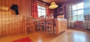 A wooden interior with a dining table and chairs, a hanging lamp, and a window with curtains. - Sauna | Wi-Fi | Terrace | Wood stove | Cable TV (Lofsdalen)