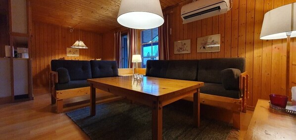 Ein gemütliches Zimmer mit Holzvertäfelung, einer Couch, einem Tisch und einer Lampe.