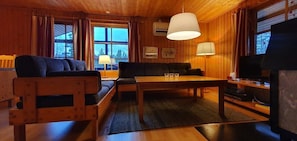 Ein Holzblockhaus-Innenraum mit einer Couch, einem Tisch und einem Fernseher.
