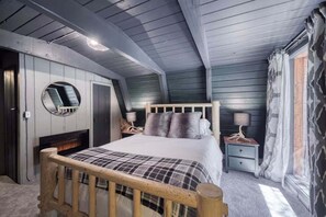 Ein Schlafzimmer mit einem hölzernen Bettgestell, einem runden Spiegel, einem Nachttisch mit Lampe und einem Fenster mit Vorhängen.