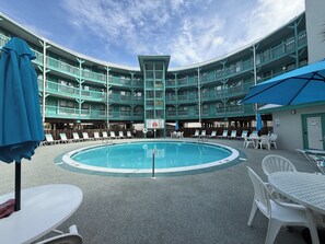 Ein Poolbereich mit kreisförmigem Pool, mehreren Balkonen und Sitzgelegenheiten im Freien.