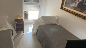 A bedroom with two beds, a nightstand with a lamp, and a window with blinds. - Deluxe Room 2 (Foz do Iguaçu)
