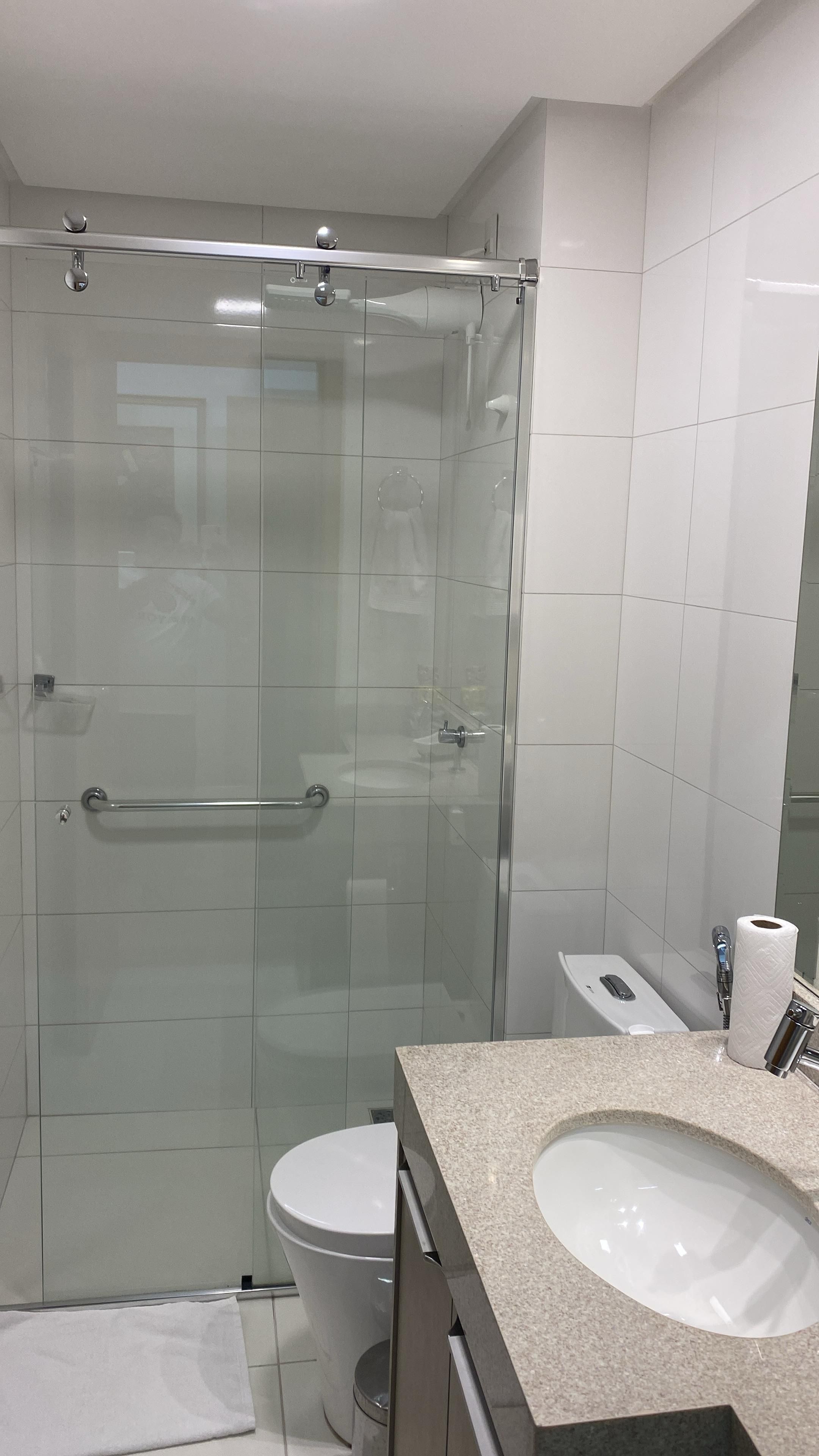 A modern bathroom with a glass-enclosed shower, a white sink, and a toilet.