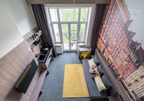 Ein modernes Wohnzimmer mit einer Couch, einem gelben Teppich, einem Fernseher und einem Fenster mit Vorhängen.