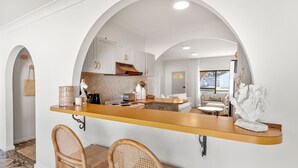 Una cucina moderna con isola centrale, mobili bianchi e vista sull'area living.