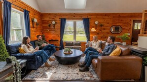 Ein gemütliches Zimmer mit Holzwänden, einem großen Fenster, einem runden Couchtisch und einer Couch.