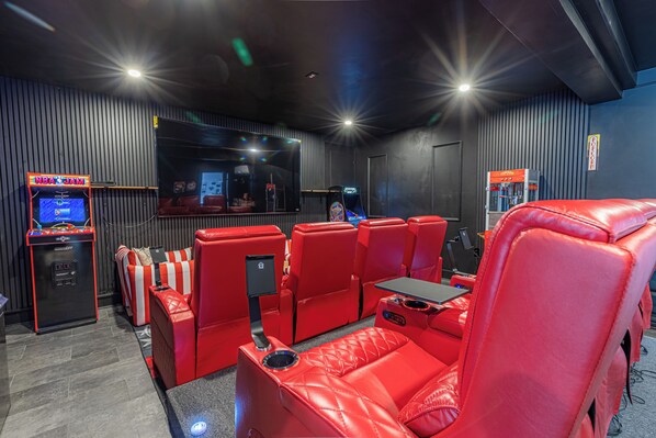 Una sala de cine con asientos de cuero rojo, una máquina de palomitas y una pantalla.