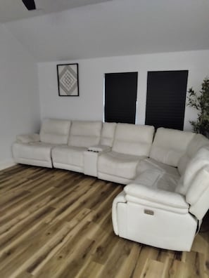 Un sofá modular en una habitación con suelo de madera y un cuadro con marco negro en la pared.