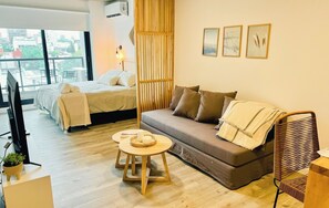 Una habitación moderna con cama, sofá y dos mesitas redondas.
