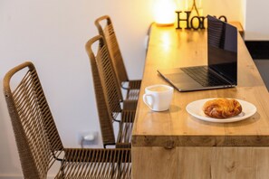 Ein Holztisch mit einem Laptop, einer weißen Tasse und einem Croissant.