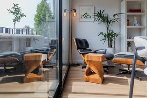 Ein modernes Interieur mit Glastrennwand, Holzmöbeln und Zimmerpflanzen.
